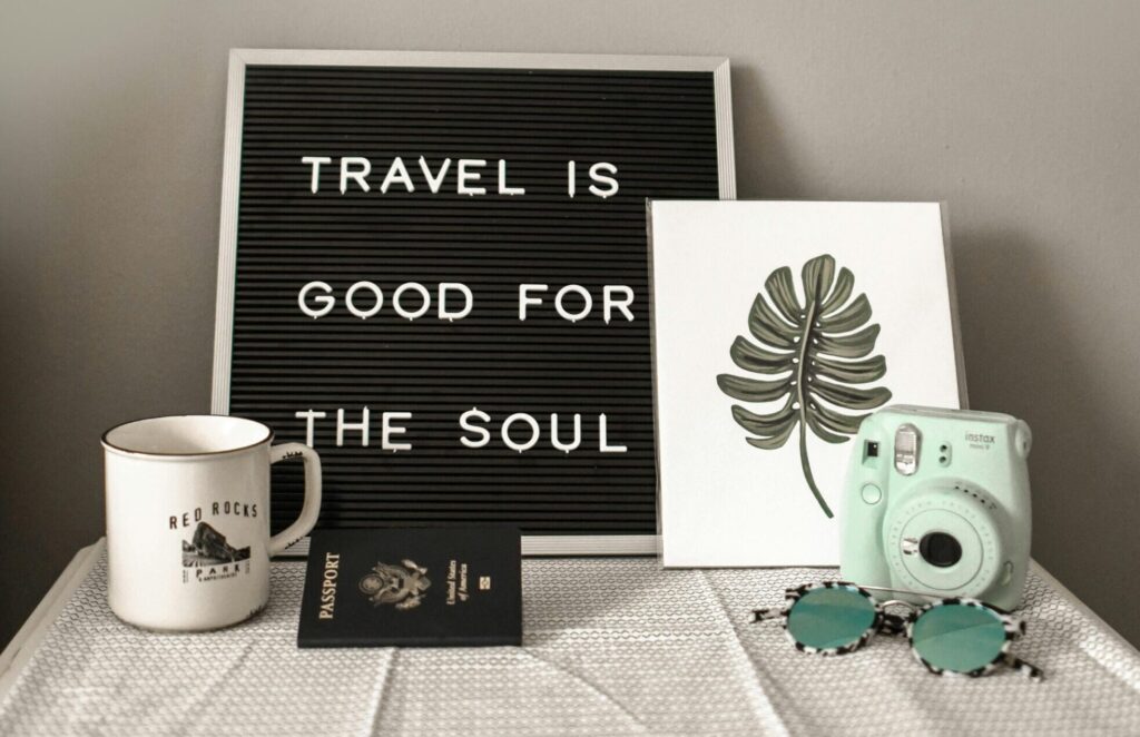 A travel-themed flat lay with a camera, coffee, and motivational quote.